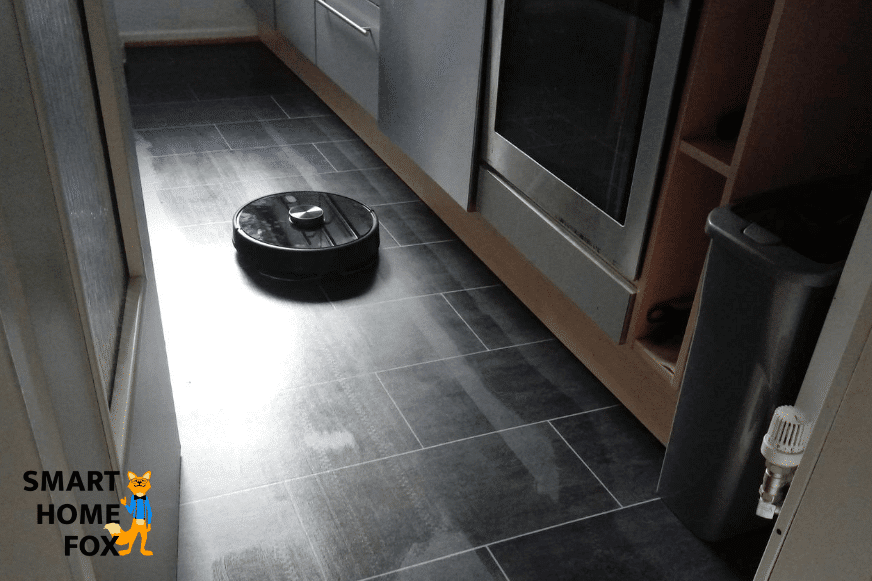 Ein Saugroboter reinigt einen Laminatboden in der Küche